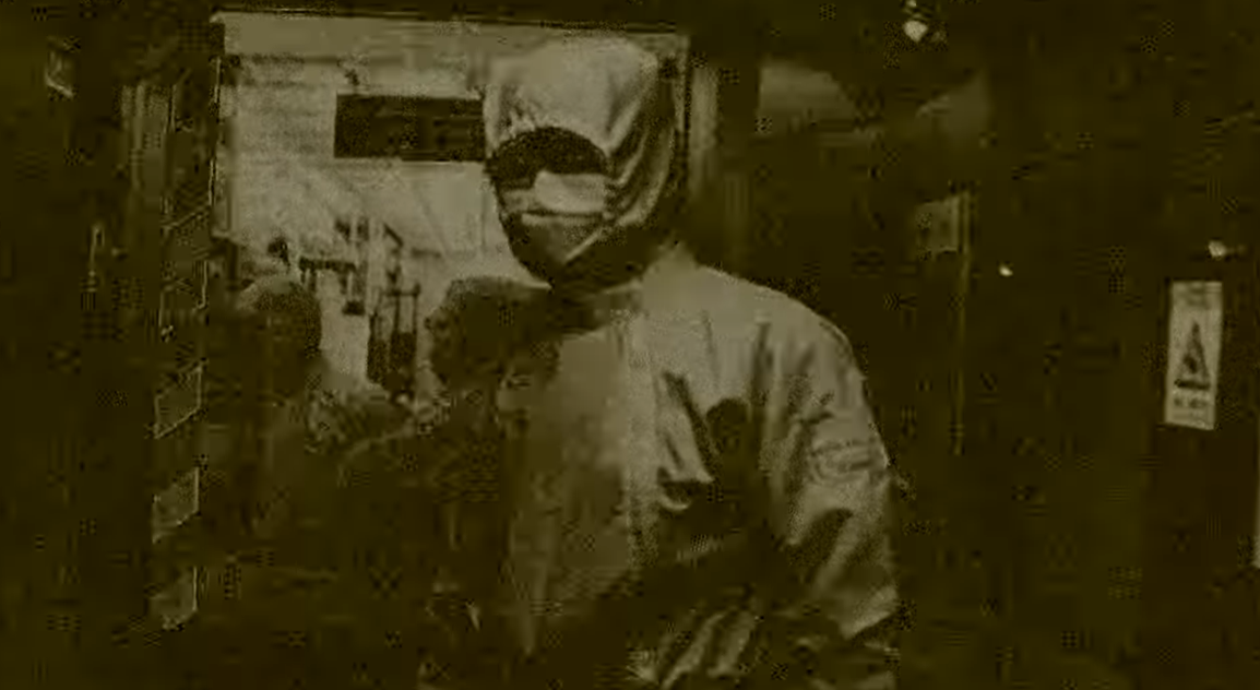 이은희 작가의 전시 '무색무취' 작품 중 장면 1. 연구복을 입은 사람이 마스크를 쓰고 서 있다.